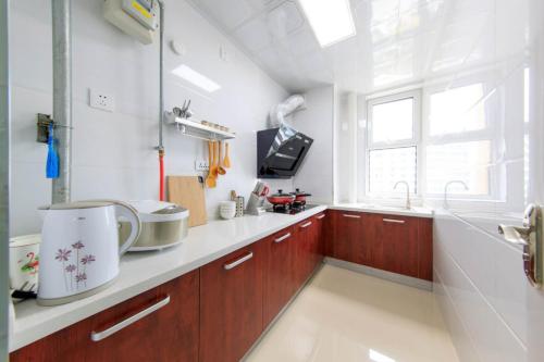 a kitchen with wooden cabinets and a sink and a window at Baoding Lianchi·Baoding East Station· Locals Apartment 00163450 in Baoding
