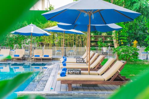 un gruppo di sedie e ombrelloni accanto alla piscina di Hoi An Rosemary Boutique Hotel & Spa a Hoi An