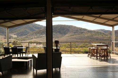 a patio with tables and chairs and a view of a mountain at Pichi Richi Park in Quorn