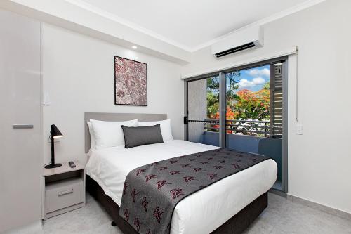 a bedroom with a large bed and a window at Argus Hotel Darwin in Darwin