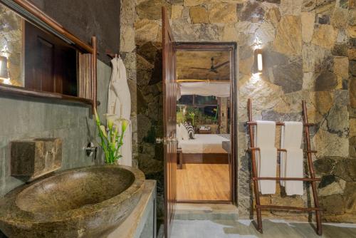 a bathroom with a large stone wall at 98 Acres Resort & Spa in Ella