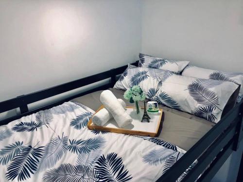 a bed with a black and white comforter and a tray with a plant at D'pristine by Antlerzone in Johor Bahru
