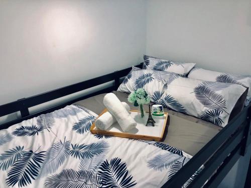 a bed with a black and white comforter and a tray with towels at D'pristine by Antlerzone in Johor Bahru