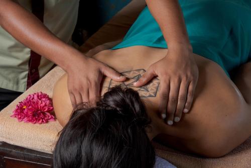 a woman getting a back massage from a therapist at 98 Acres Resort & Spa in Ella