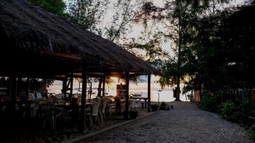 un restaurante con mesas y sillas y techo de paja en Adang Sea Divers & Eco Lodge, en Ko Lipe