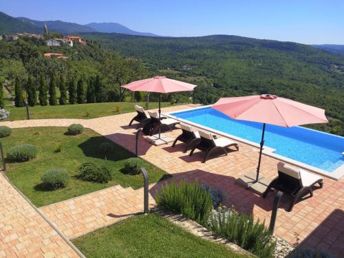een zwembad met parasols en stoelen en een zwembad met visorangeringktop bij Home Andrea with infinity salty pool in Roč