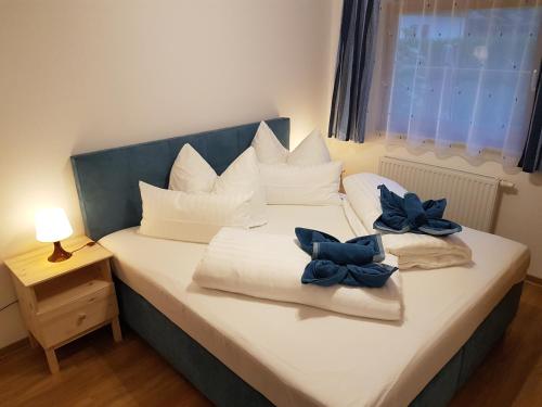 a bed with white pillows and blue bows on it at Ferienwohnung Dominik in Neustift im Stubaital
