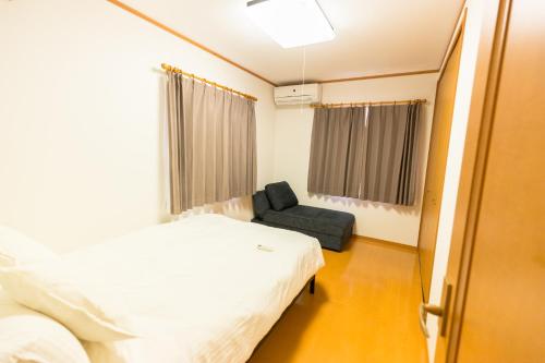 um quarto de hospital com uma cama e uma cadeira em Airstar Chiyo House x M&Z HOUSE em Fukuoka