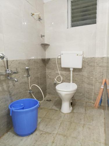 a bathroom with a toilet and a blue bucket at Greens Residency in Bengaluru