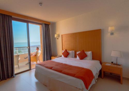 a hotel room with a bed and a view of the ocean at Ramada Resort Dead Sea in Sowayma