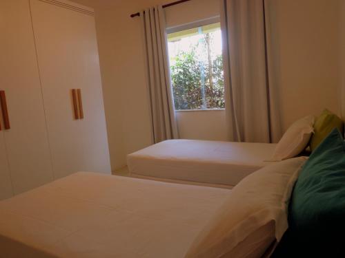 two beds in a room with a window at Apartamentos Breezes com verde, sossego e preço justo - ideal para famílias e amigos em Imbassaí in Imbassai