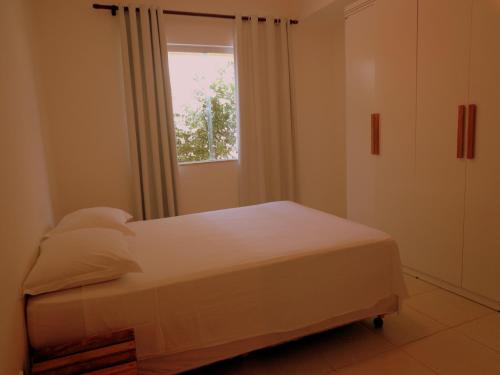 a small bedroom with a bed and a window at Apartamentos Breezes com verde, sossego e preço justo - ideal para famílias e amigos em Imbassaí in Imbassai