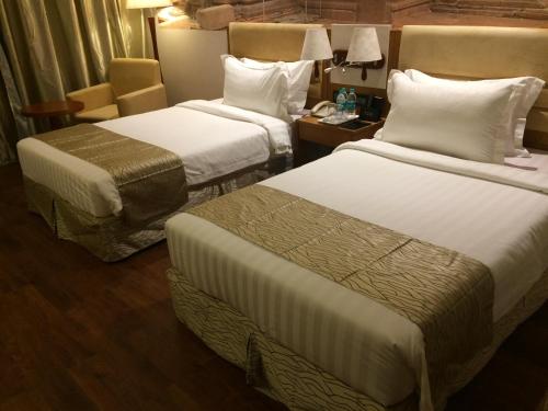 a hotel room with two beds and a chair at Regenta Central RS Chennai OMR SIPCOT in Chennai