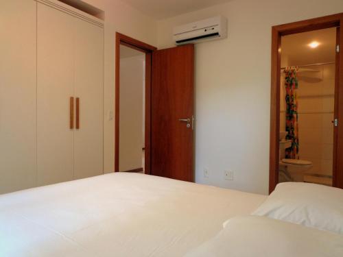 a bedroom with a white bed and a closet at Apartamentos Breezes com verde, sossego e preço justo - ideal para famílias e amigos em Imbassaí in Imbassai