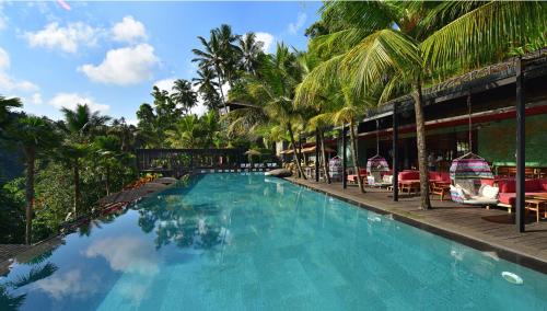 a swimming pool next to a resort with palm trees at Chapung Sebali Resort in Ubud