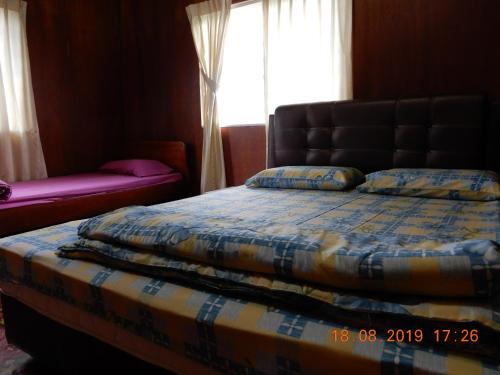 a bedroom with a bed and a window at Bulan And Daud Homestay in Bario