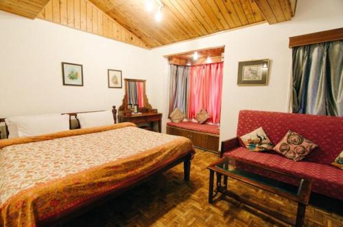 a bedroom with a bed and a red couch at The Hive Cottage By Royal Collection Hotels in Nainital