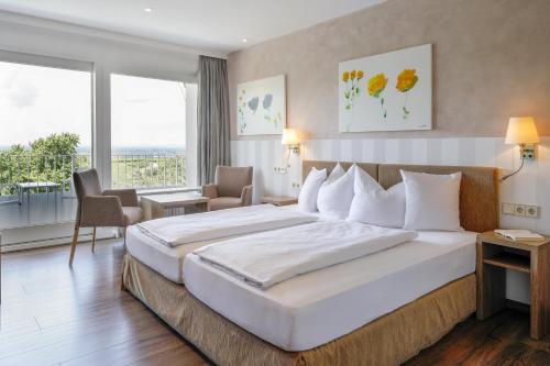 a bedroom with a large bed and a large window at Hotel Rebenhof in Baden-Baden