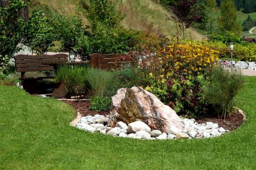 a rock in the middle of a garden with a bench at Pension Bartlhof in Lermoos