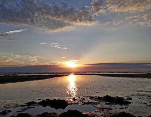 a sunset on the beach with the sun setting at Strandhotel Zoomers in Castricum