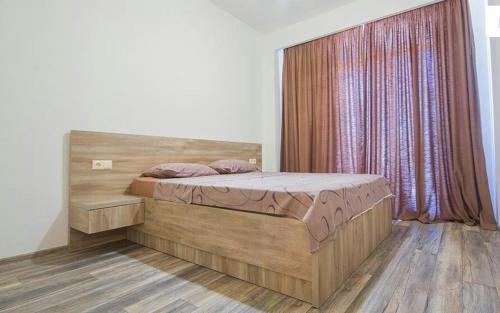 een slaapkamer met een groot houten bed en een raam bij Tikas home Апартаменты in Tbilisi City