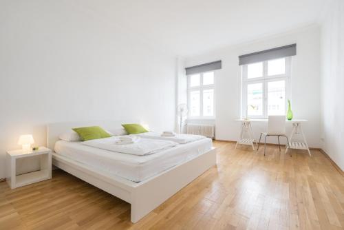 a white bedroom with a large white bed and wooden floors at Kaiser-Friedrich in Berlin