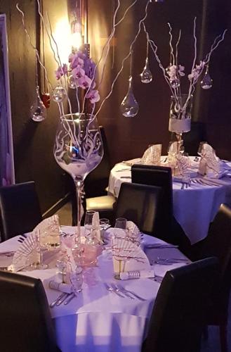 a table with white clothed tables with purple flowers in a vase at Le Relais Des Chateaux Forts in Bitche