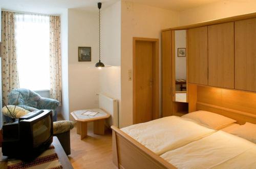 1 dormitorio con 1 cama, 1 silla y TV en Landgasthof Tarp en Tarp
