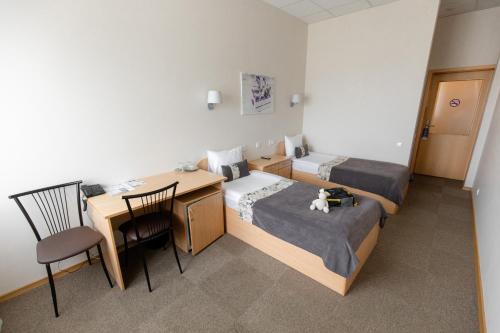 a small room with two beds and a desk and a table at Sports Hotel in Valmiera