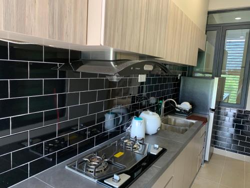 eine Küche mit schwarzen Wandfliesen und einem Waschbecken in der Unterkunft SweetHome 3BR@P'Residence Apartment 1226Sft 6 in Kuching