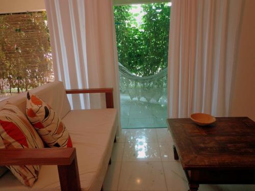 a living room with a couch and a table and a window at Apartamentos Breezes com verde, sossego e preço justo - ideal para famílias e amigos em Imbassaí in Imbassai