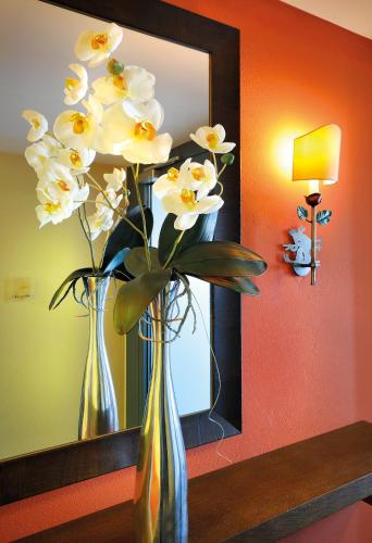 two vases with white flowers in front of a mirror at Apparthotel Sonne in Obertauern