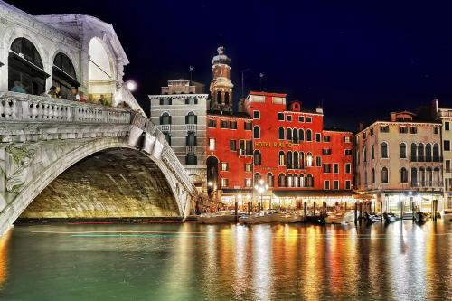 un ponte su un fiume in una città di notte di Hotel Rialto a Venezia