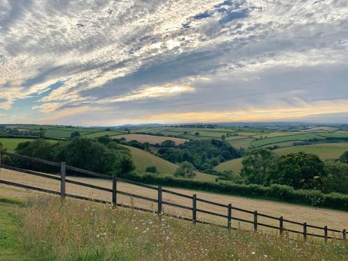 a fence on a hill next to a river at Kerswell Farmhouse in Totnes