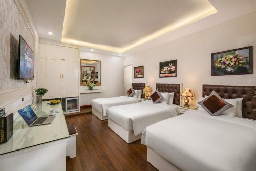 a hotel room with two beds and a desk at TrangTrang Boutique Hotel in Hanoi