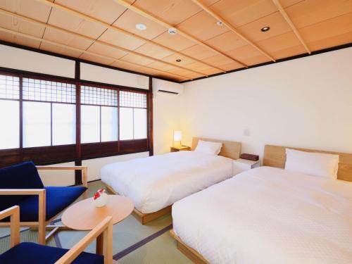 a bedroom with two beds and a table and a chair at NIPPONIA HOTEL Takehara Saltworks Town in Takekara
