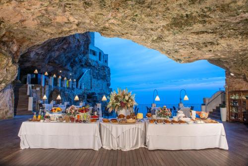 einen Tisch vor einer Höhle mit Essen drauf in der Unterkunft Hotel Grotta Palazzese in Polignano a Mare
