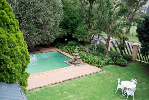 a small pool with a table and chairs in a yard at Greenfields Guesthouse & Restaurant in Alberton