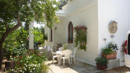 um pátio com uma mesa, cadeiras e flores em Il Trullo del Cadetto em Francavilla Fontana