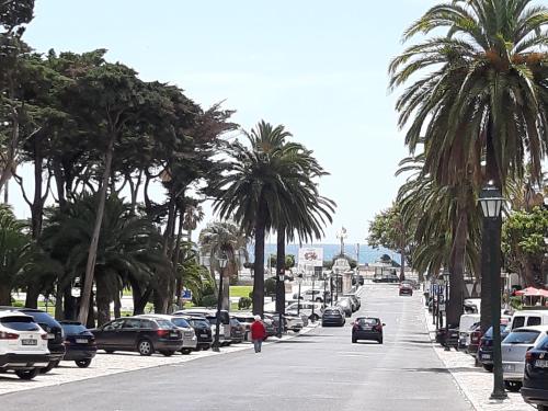a person walking down a street with palm trees and cars at BEACHFRONT Cascais,Estoril Apartment in Estoril