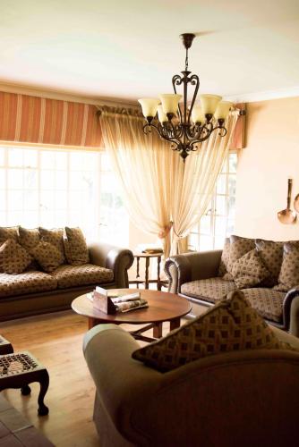 a living room with couches and a chandelier at Greenfields Guesthouse & Restaurant in Alberton