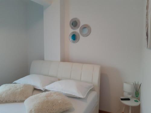 a white couch with pillows and a clock on the wall at Apartman DIJANA in Banja Luka