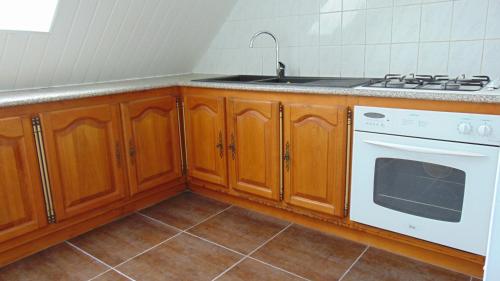 cocina con armarios de madera y horno de fogón blanco en chez MARIA, en Coucy-le-Château-Auffrique