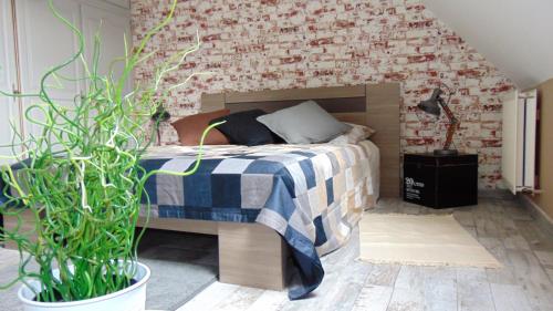 een slaapkamer met een bed en een bakstenen muur bij chez MARIA in Coucy-le-Château-Auffrique