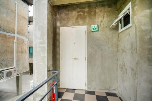 a white door in a room with a checkered floor at Matini Ratchada 32 in Bangkok
