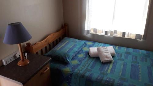 1 dormitorio con 1 cama con lámpara y toallas en Blue Horizon Flat 8, en Jeffreys Bay