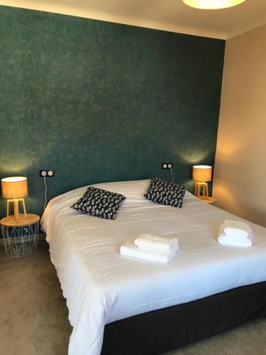 une chambre avec un grand lit blanc avec deux lampes dans l'établissement La bacchante, à Saint-Hippolyte