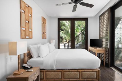 a bedroom with a white bed and a television at El Nido Resorts Miniloc Island in El Nido