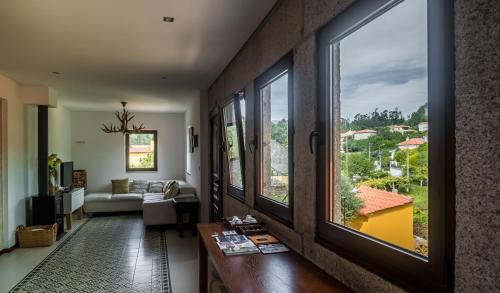 a living room with large windows and a couch at Casas do Prazo - Turismo Rural in Nogueira