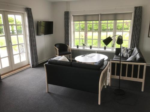 ein Wohnzimmer mit einem Tisch, Stühlen und Fenstern in der Unterkunft Bed & Breakfast v/Pia Sørensen in Fredericia